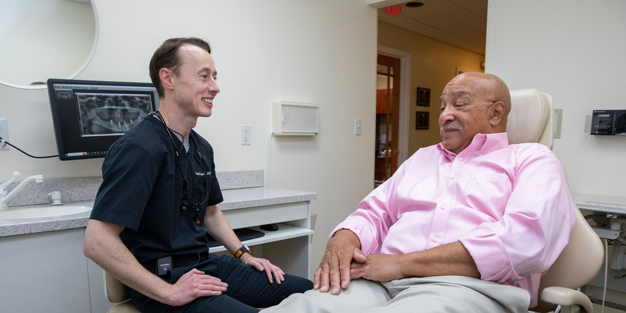 dental implant patient smiling talking with doctor